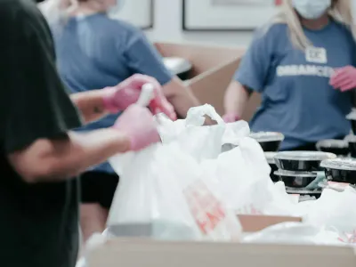 Volunteers in gloves packing food parcels