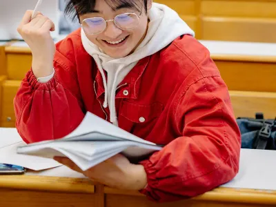 A student working through notes at a lecture hall desk